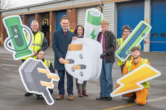 First bus employees and Cllr Widdowson holding giant plug socket.