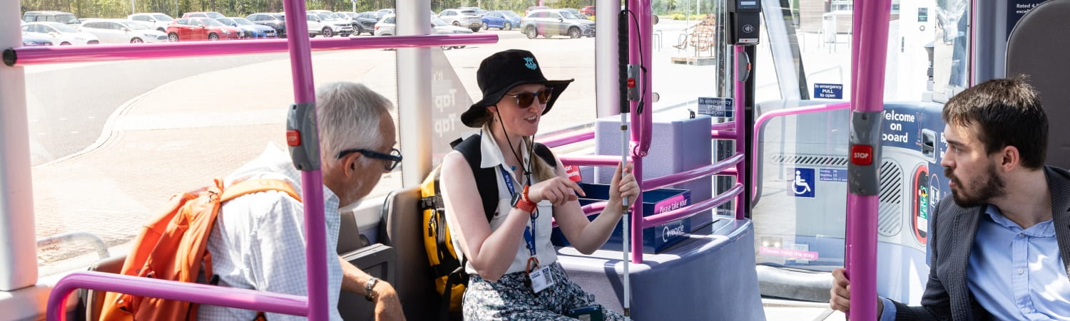Passengers seated inside an accessible bus with priority seating area.